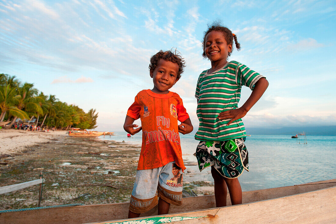 Kleiner Junge und kleines Mädchen auf einem Auslegerkanu am Strand, Biak, Papua, Indonesien, Asien