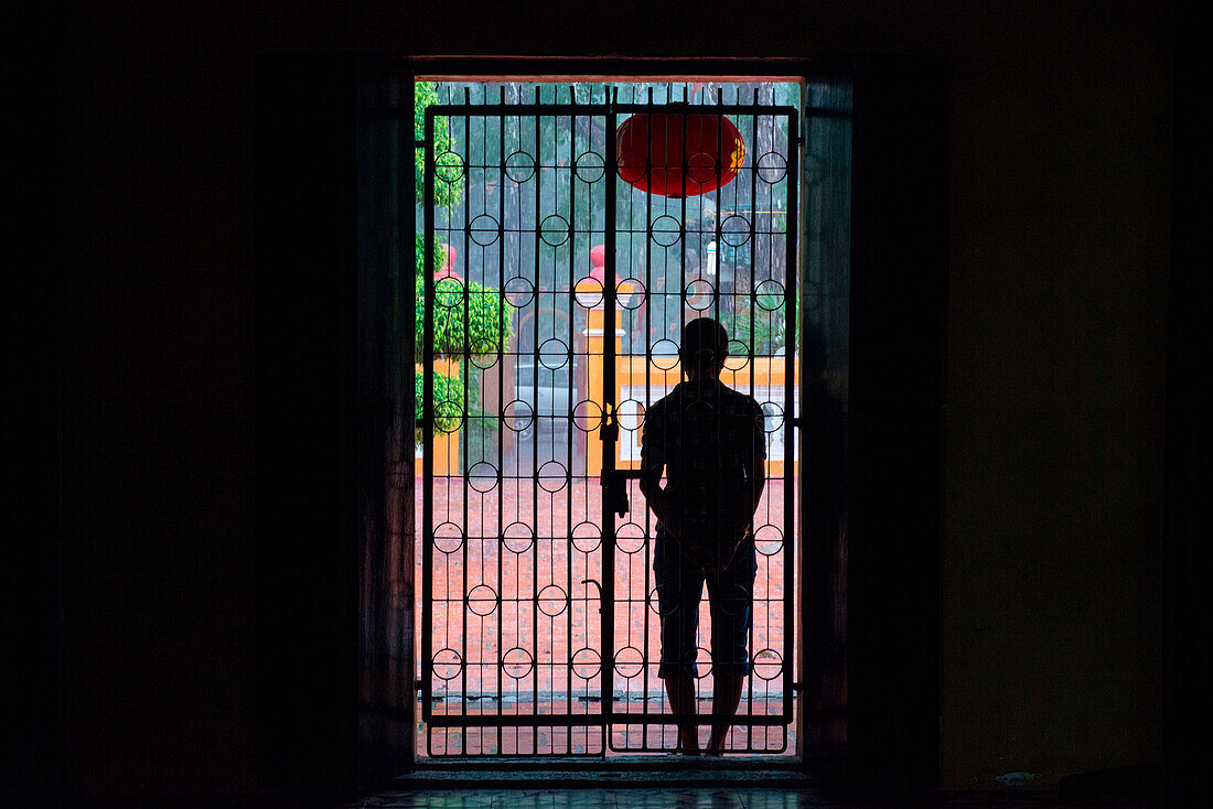 Silhouette of man in temple doorway during downpour, Ho Chi Minh City (Saigon), Ho Chi Minh, Vietnam, Asia