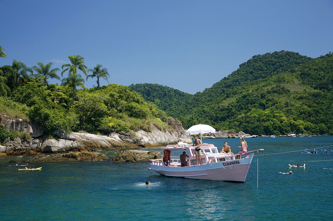 Tourist on a chartered fishing boat cruising between the different beaches and islands around Parati, Rio de Janeiro State, Brazil, South America