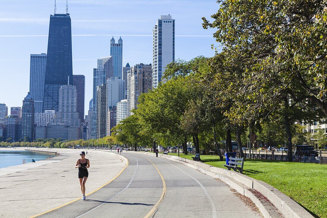 Jogger on North Avenue Beach with John Hancock Center and city skyline behind, Chicago, Illinois, United States of America, North America