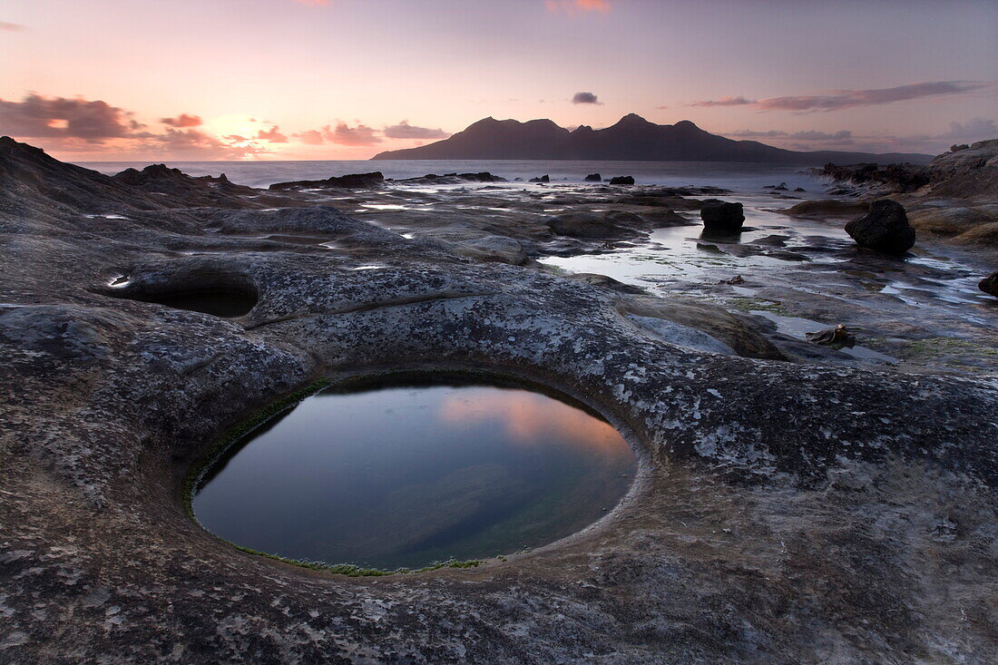 View towards Isle of Rum at sunset from rock formation at Laig Bay, Isle of Eigg, Inner Hebrides, Scotland, United Kingdom, Europe