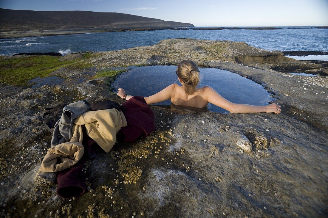 Woman relaxing in natural pool by the Atlantic Ocean, Santa Cruz, Argentina, South America