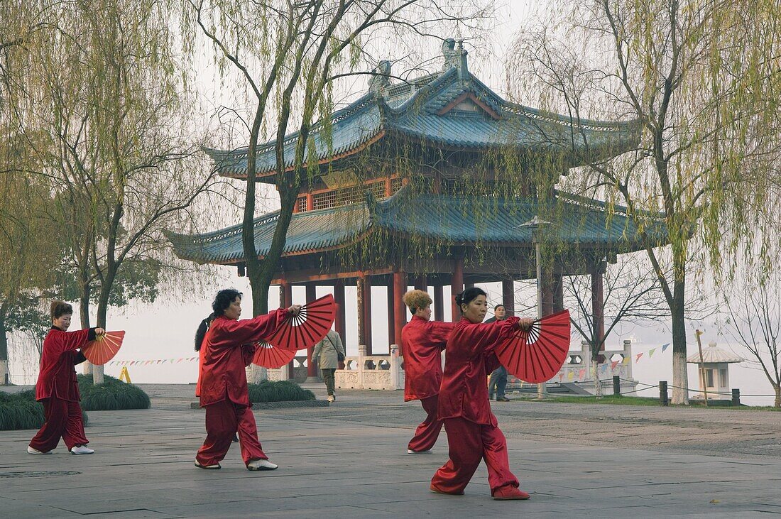 Women practising tai chi in front of a pavilion on West Lake, Hangzhou, Zhejiang Province, China, Asia