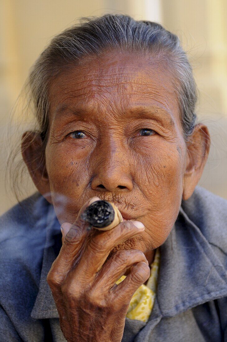 Old woman smokes a marihuana cigar, Bagan, Myanmar, Asia