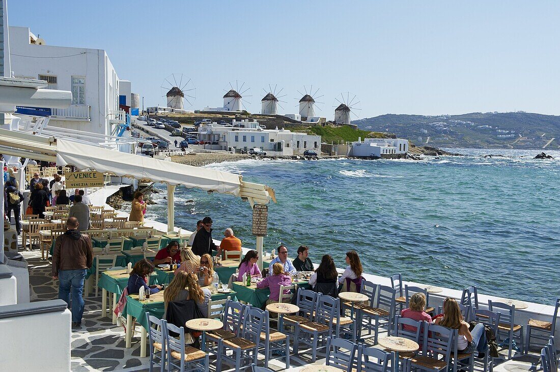 Cafe bar on the sea side with the five windmills (Kato Mili) beyond, Little Venice, Mykonos Town, Chora, Mykonos Island, Cyclades, Greek Islands, Greece, Europe