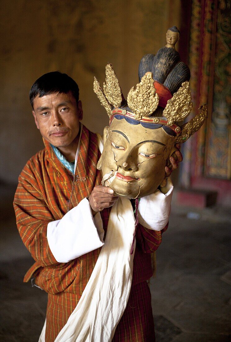 Local man holding an old golden mask with cracks visible in the face, Gangtey Tsechu at Gangte Goemba, Gangte, Phobjikha Valley, Bhutan, Asia