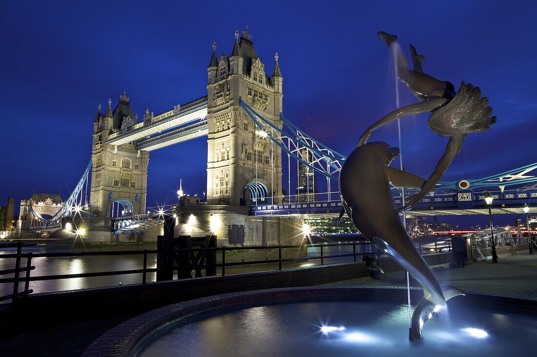 Girl With A Dolphin, statue by David Wynne, illuminated at night in front of Tower Bridge,  London, England, United Kingdom, Europe