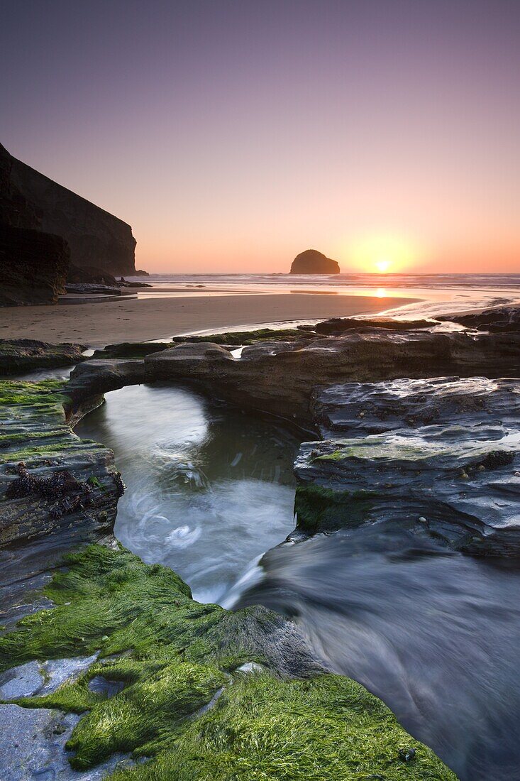 Water channel flowing beneath natural rock arch at Trebarwith Strand beach in Cornwall, England, United Kingdom, Europe