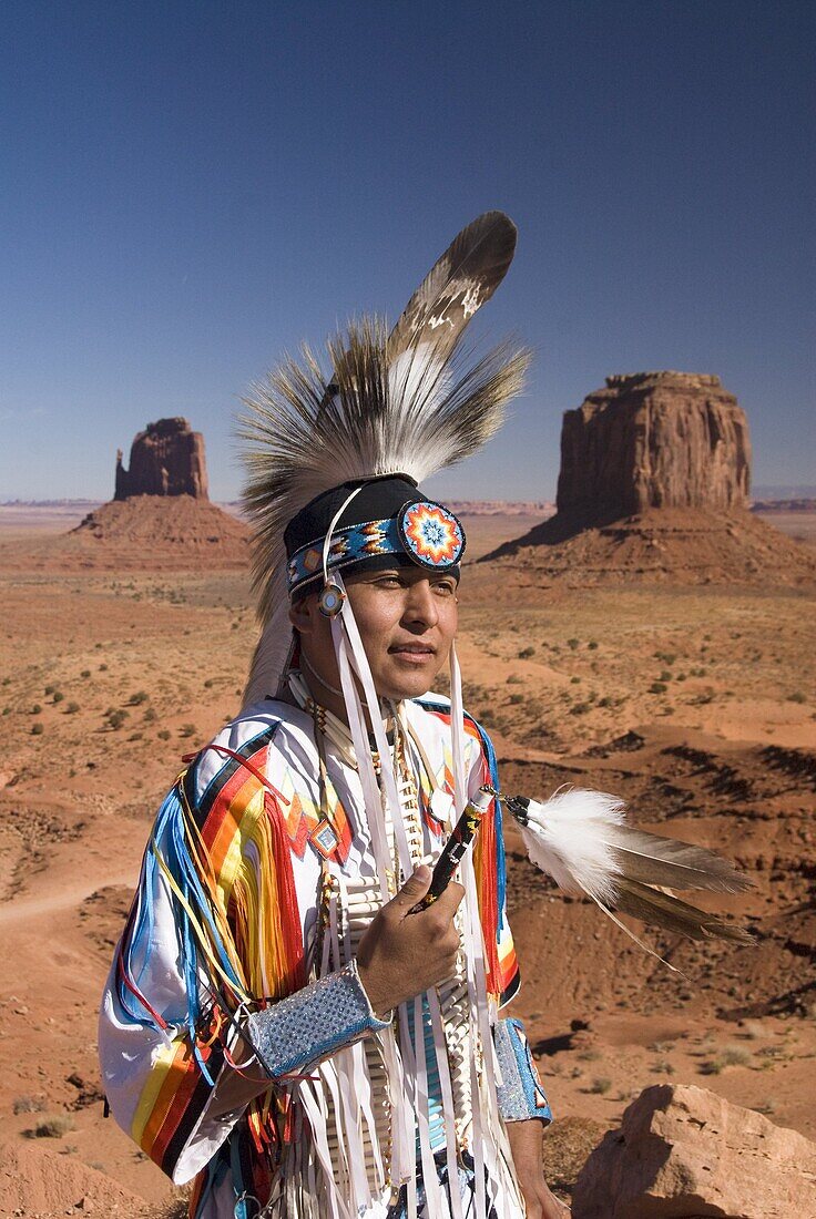 Navajo man in traditional costume, with Merrick Butte on the right and East Mitten Butte on the left in the background, Monument Valley Navajo Tribal Park, Arizona, United States of America, North America