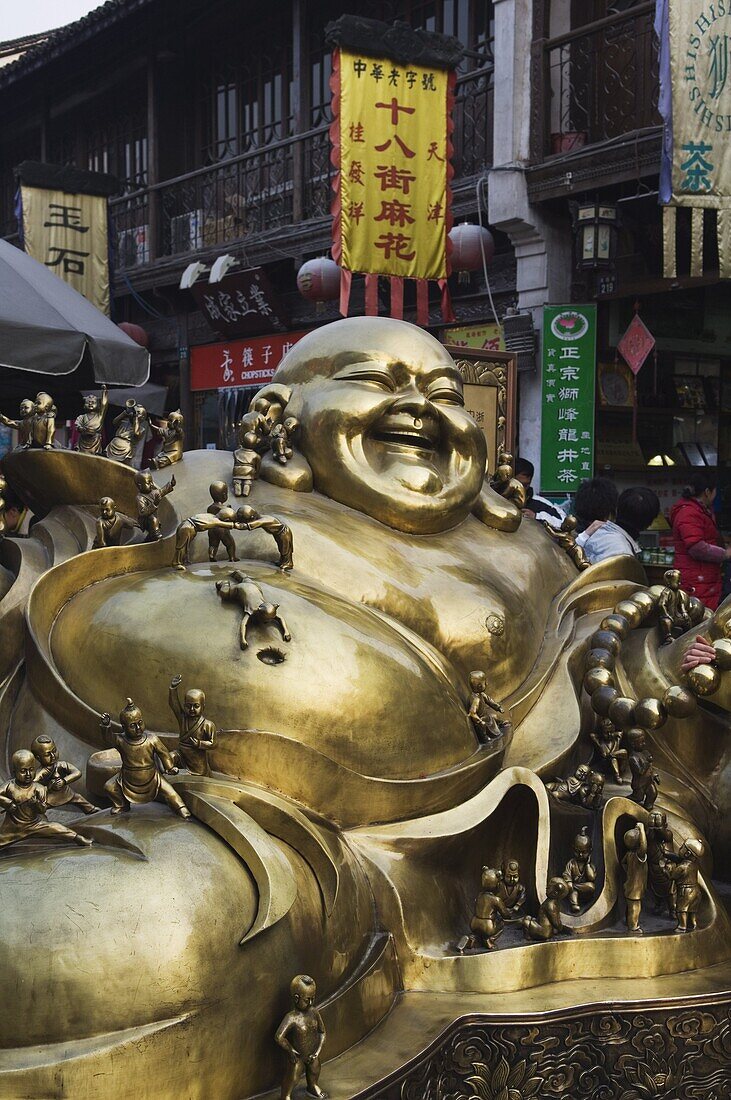 A golden statue of a reclining laughing Buddha covered in small Buddhas, Qinghefang Old Street in Wushan district of Hangzhou, Zhejiang Province, China, Asia