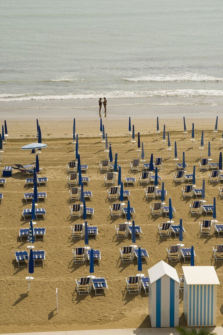 Quiet beach with beach hut, one umbrella open, and two people at waters edge, Jesolo, Veneto, Italy, Europe