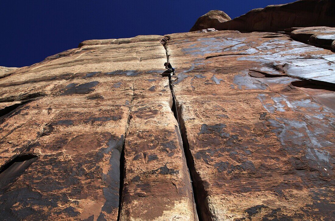A rock climber tackles an overhanging crack in a sandstone wall on the cliffs of Indian Creek, a famous rock climbing area in Canyonlands National Park, near Moab, Utah, United States of America, North America