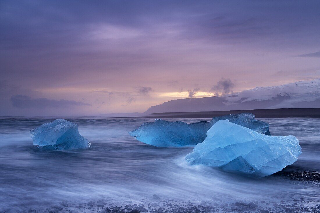 Icebergs washed ashore on Breidamerkursandur black sands, near Jokulsarlon glacial lagoon, Oraefajokull (Vatnajokull) glacier in the distance, East Iceland, Iceland, Polar Regions
