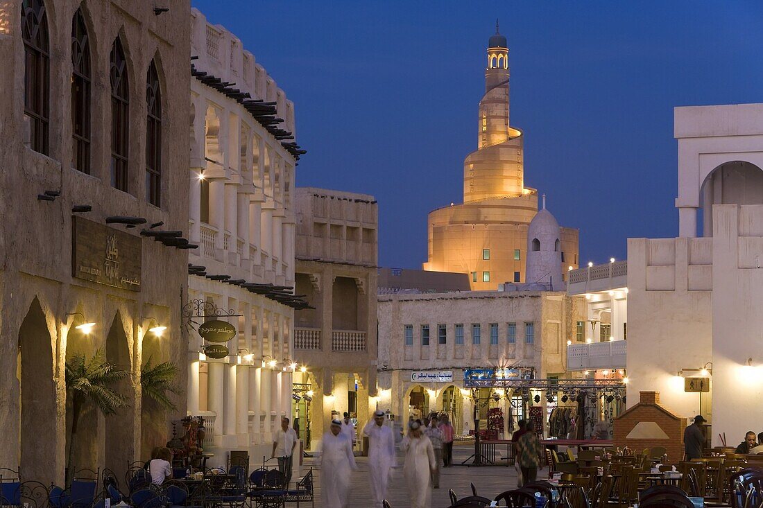 The restored Souq Waqif looking towards the illuminated spiral mosque of the Kassem Darwish Fakhroo Islamic Centre based on the Great Mosque in Samarra in Iraq, Doha, Qatar, Middle East