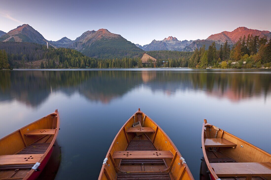 Rowing boats and mountains beneath a twilight sky in autumn, Strbske Pleso Lake in the High Tatras, Slovakia, Europe