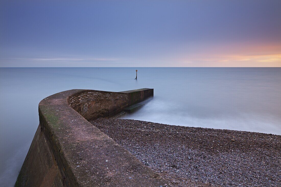 Stone jetty on Sidmouth beachfront at sunset, Sidmouth, Devon, England, United Kingdom, Europe