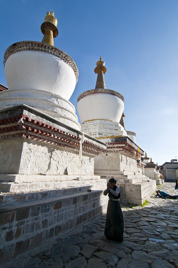 Pilgrim in front of the white stupas at the Tashilumpo monastery, Shigatse, Tibet Autonomous Region, China, Asia