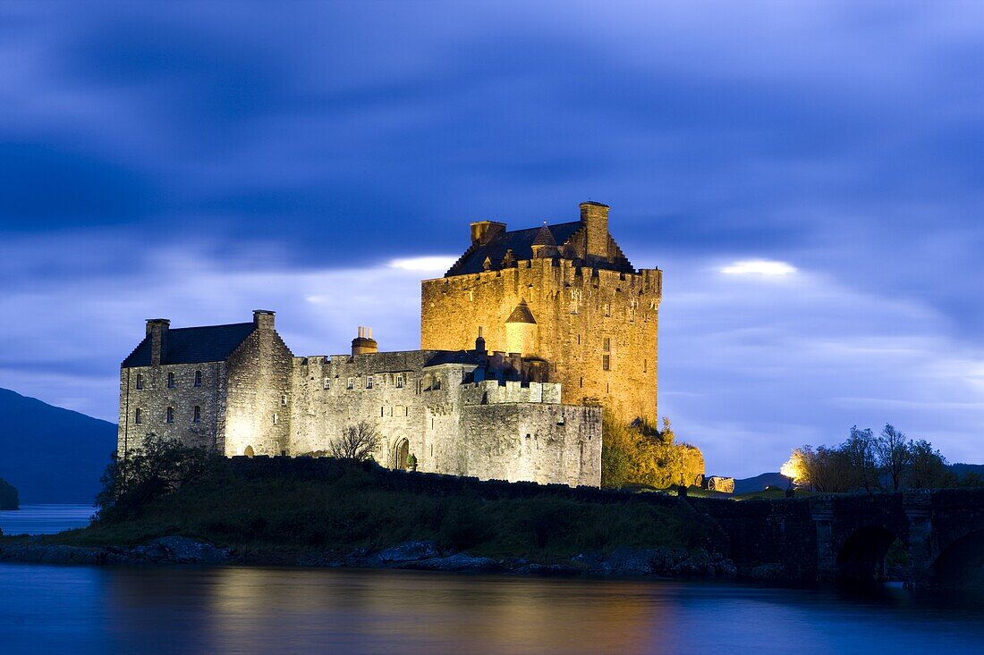 Eilean Donan Castle floodlit against deep blue twilight sky and water of Loch Duich, near Dornie, Kyle, Highlands, Scotland, United Kingdom, Europe