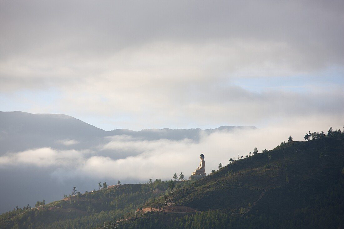 Misty early morning view of giant golden Buddha being constructed on a forested hillside outside Thimpu, Bhutan, Asia