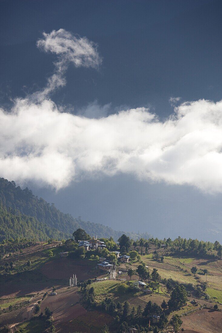 Village of Shingyer against a dramatic backdrop of mountains and clouds, Phobjikha Valley, Bhutan, Himalayas, Asia