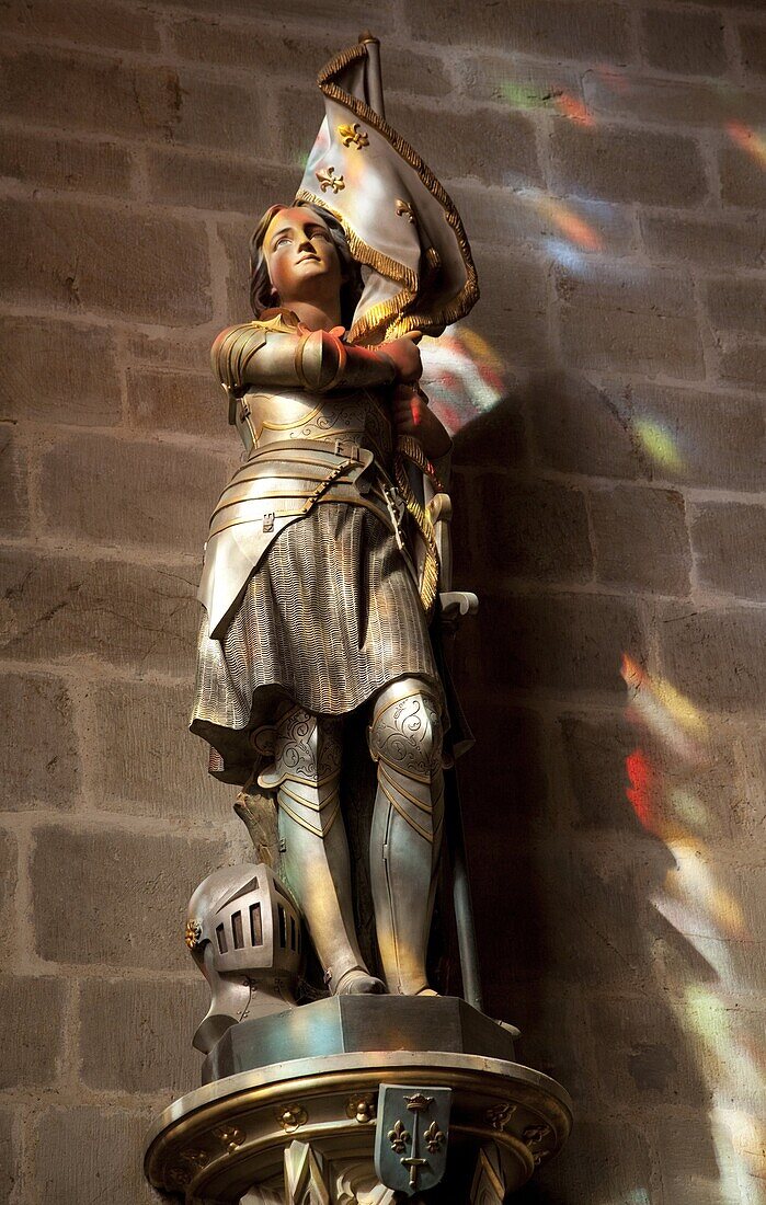 Statue of St. Joan of Arc with coloured light from stained glass, Church of Notre Dame, Vitre, Brittany, France, Europe