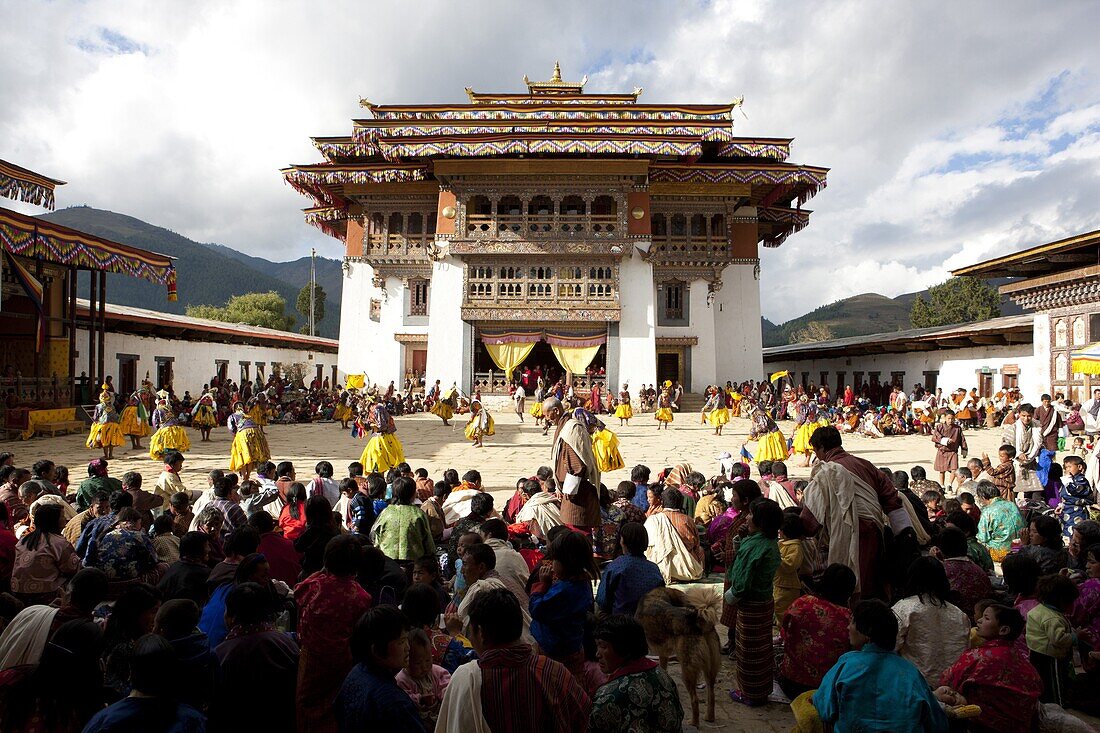 View over crowds of spectators to the main courtyard during a masked dance by Buddhist monks at Gangtey Tsechu at Gangte Goemba, Gangte, Phobjikha Valley, Bhutan, Asia