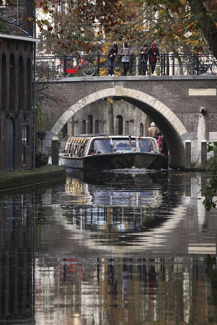 A sightseeing barge under a bridge on the Oudegracht Canal in the Dutch city of Utrecht, Utrecht Province, Netherlands, Europe
