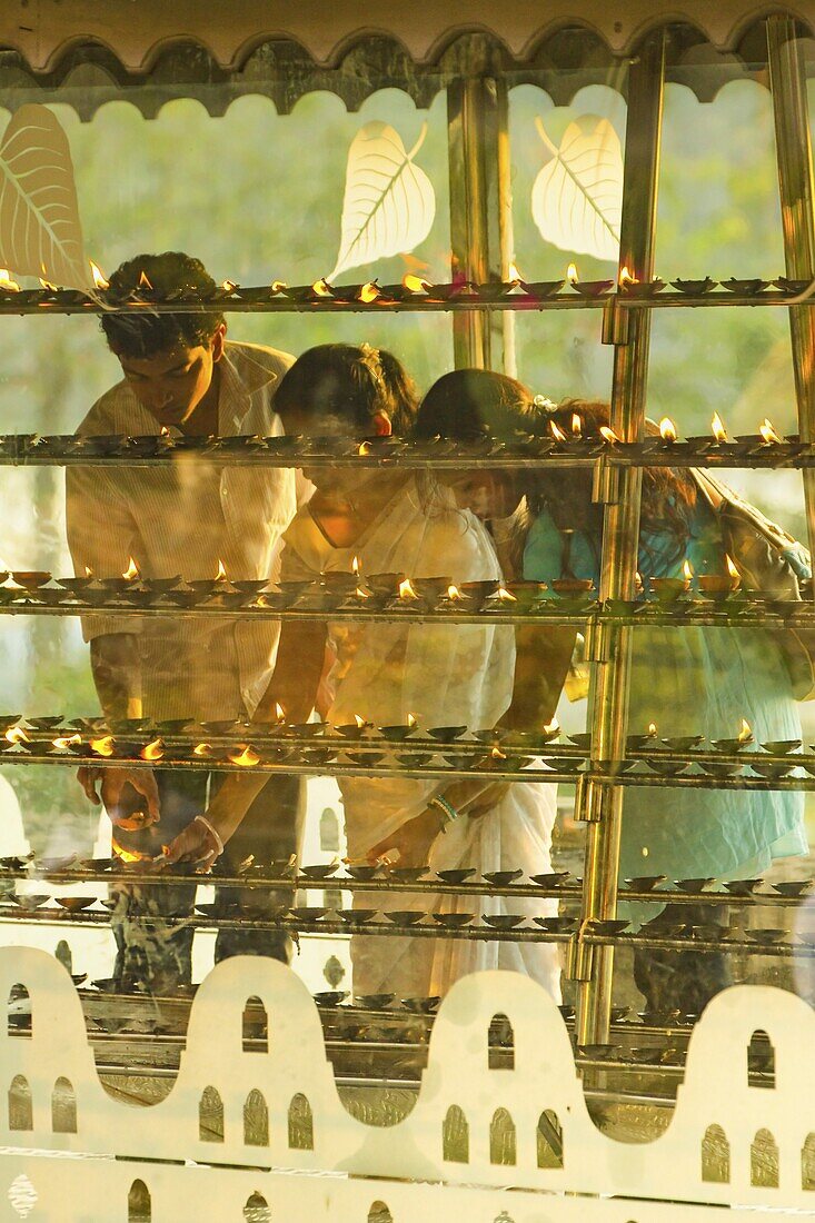 Devotees lighting candles at sunset in the Temple of the Sacred Tooth Relic (Temple of the Tooth), site of Buddhist pilgrimage, Kandy, Sri Lanka, Asia