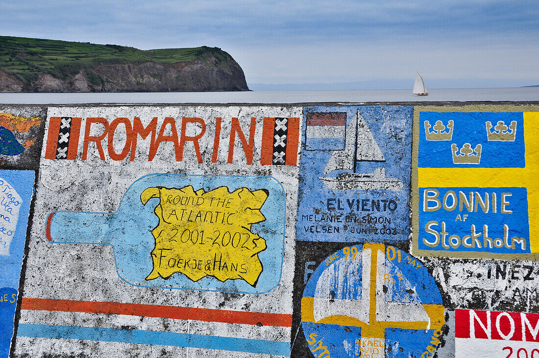 Hafen der Stadt Horta mit berühmten Malereien auf Hafenmauer und Segelschiff, im Hintergrund Steilküste, Marina da Horta, Insel Faial, Azoren, Portugal, Europa, Atlantik