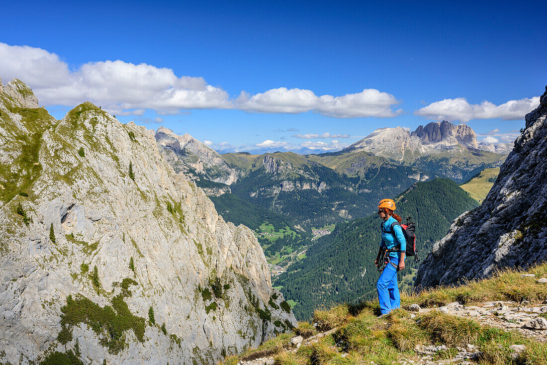 Woman hiking ascending towards Sas Aut, Langkofel in background, fixed rope route Gadotti, Vallaccia range, Marmolada, Dolomites, UNESCO World Heritage Dolomites, Trentino, Italy
