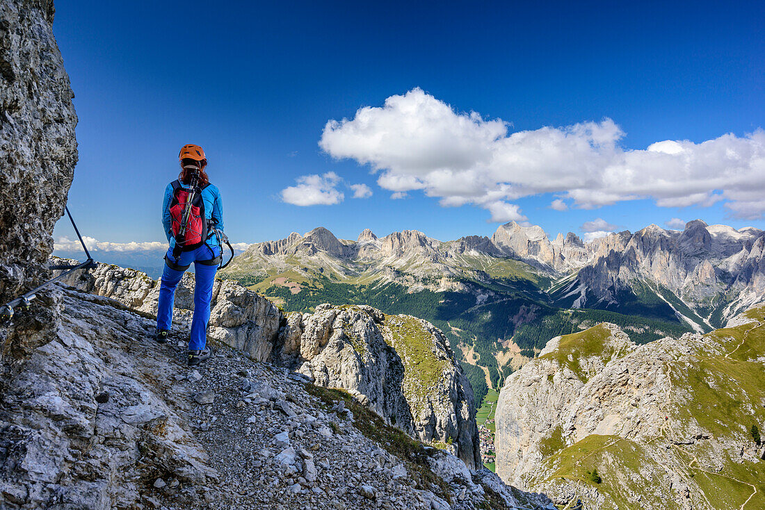Woman ascending on fixed rope route looking towards Rosengarten range, Sas Aut, Vallaccia range, Marmolada, Dolomites, UNESCO World Heritage Dolomites, Trentino, Italy