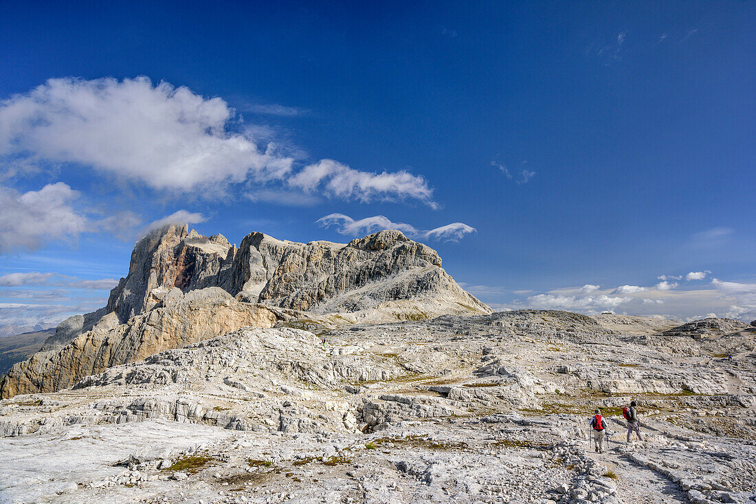 Zwei Wanderer gehen über Pala-Hochfläche, Cimon della Pala, Cima della Vezzana und Cima Corona im Hintergrund, Pala, Dolomiten, UNESCO Weltnaturerbe Dolomiten, Trentino, Italien