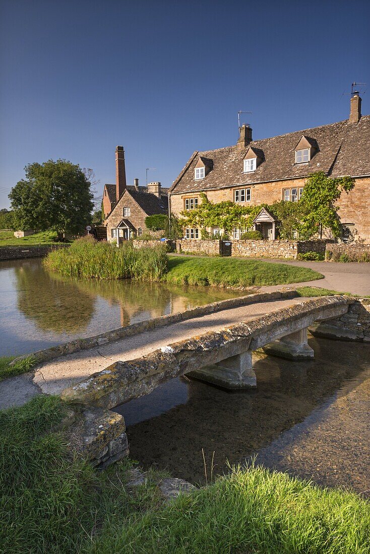 Stone footbridge and cottages in the picturesque Cotswolds village of Lower Slaughter, Gloucestershire, England, United Kingdom, Europe