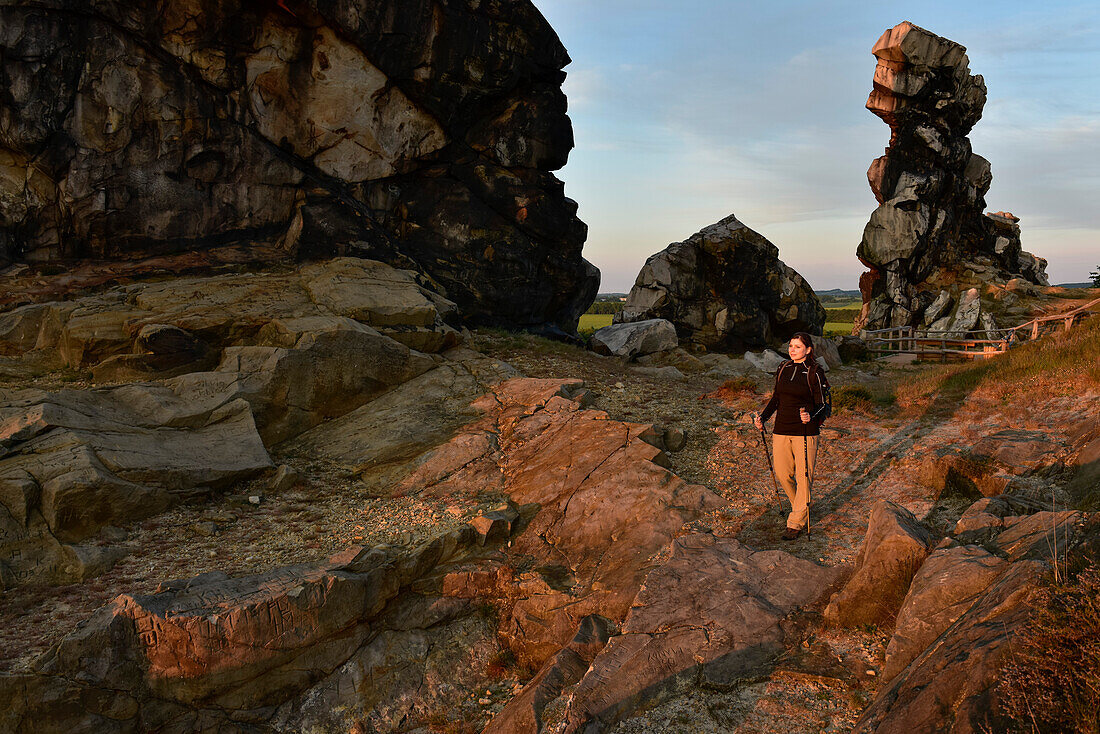 Young woman is hiking along rock formation Devil´s Wall (Teufelsmauer) at sunset, Neinstedt, Thale, Harz Foreland, Harz Mountains, Saxony-Anhalt, Germany