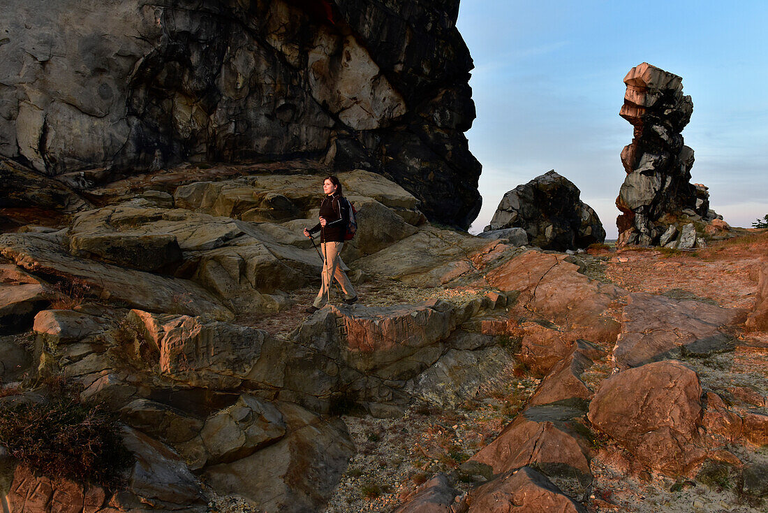Young woman is hiking along rock formation Devil´s Wall (Teufelsmauer) at sunset, Neinstedt, Thale, Harz Foreland, Harz Mountains, Saxony-Anhalt, Germany