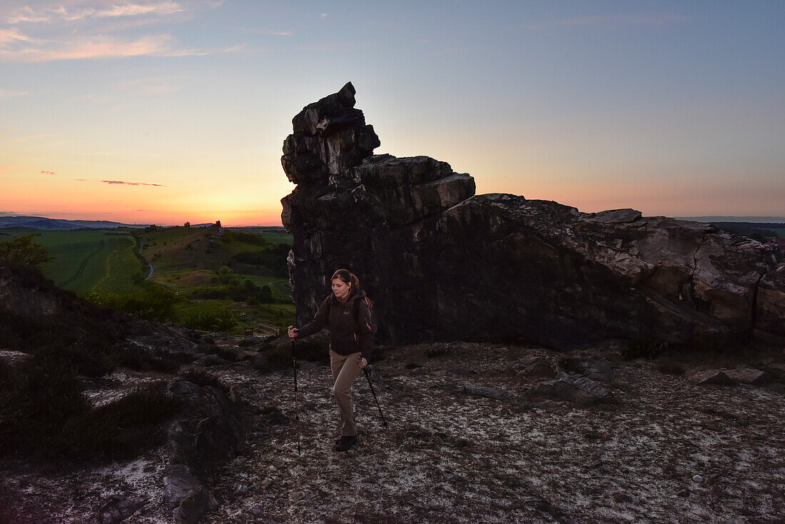 Young woman is hiking along rock formation Devil´s Wall (Teufelsmauer) at sunset, Neinstedt, Thale, Harz Foreland, Harz Mountains, Saxony-Anhalt, Germany