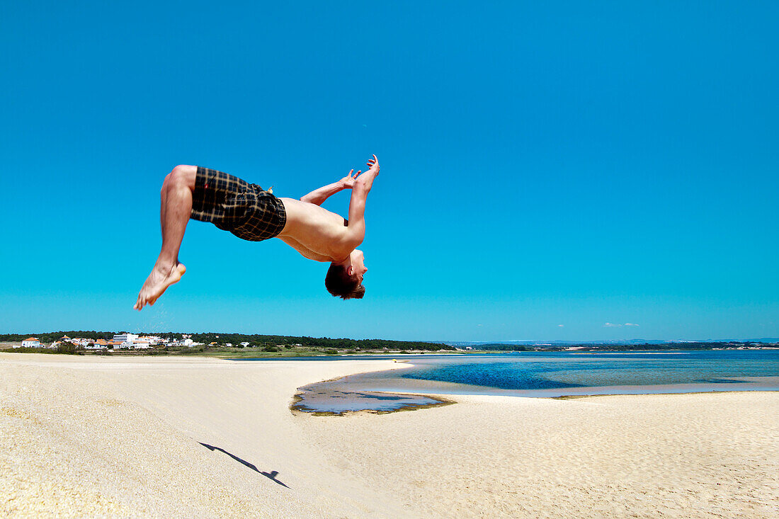 Mann springt von den Dünen, Lagoa de Santo Andre, Praia de Santo Andre, Santiago do Cacem, Costa Vicentina, Alentejo, Portugal