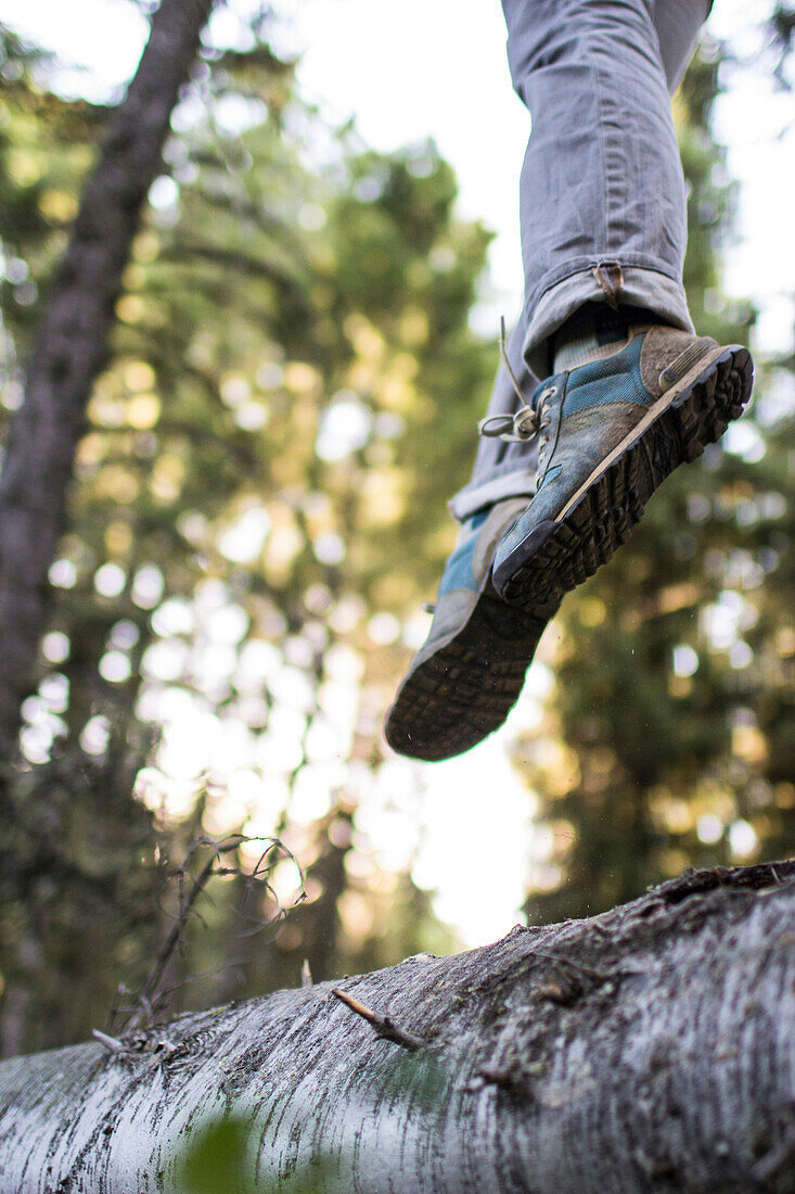 Woman jumps from a log in the forest