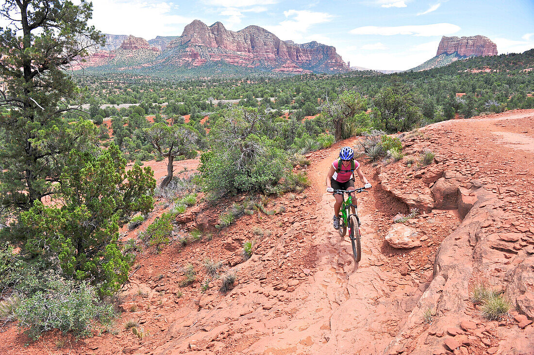 Woman rides the Templeton Trail in South Sedona, Arizona.  Templeton Trail rides over slickrock of the Cathedral Rock with views of Courthouse Butte across the way.