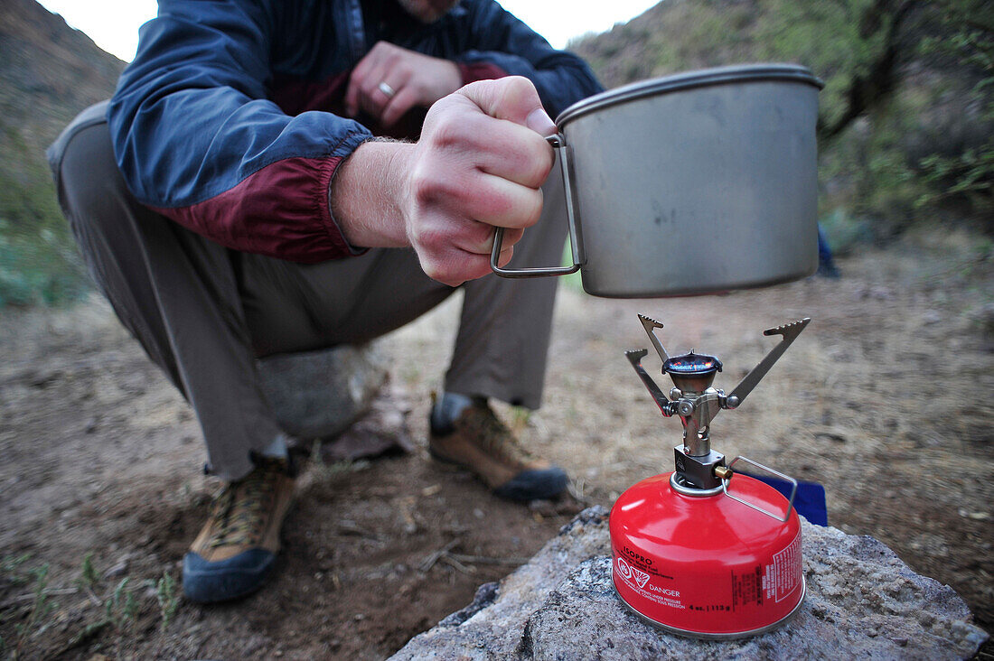 Woman and man backpackers prepare dinner with a camp stove at camp close to Charleboise Springs in La Barge Canyon on the Dutchmans Trail in the Superstition Wilderness Area, Tonto National Forest near Phoenix, Arizona November 2011.  The trail links up w