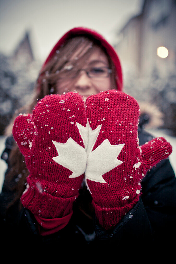 A woman places her mittens side by sde to create a  Canadian Maple Leaf.
