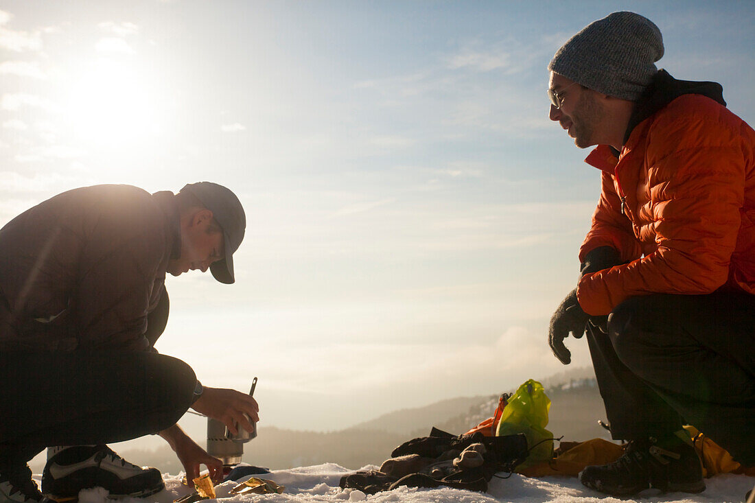 Two climbers converse while  cooking breakfast in the mountains of British Columbia, Canada.