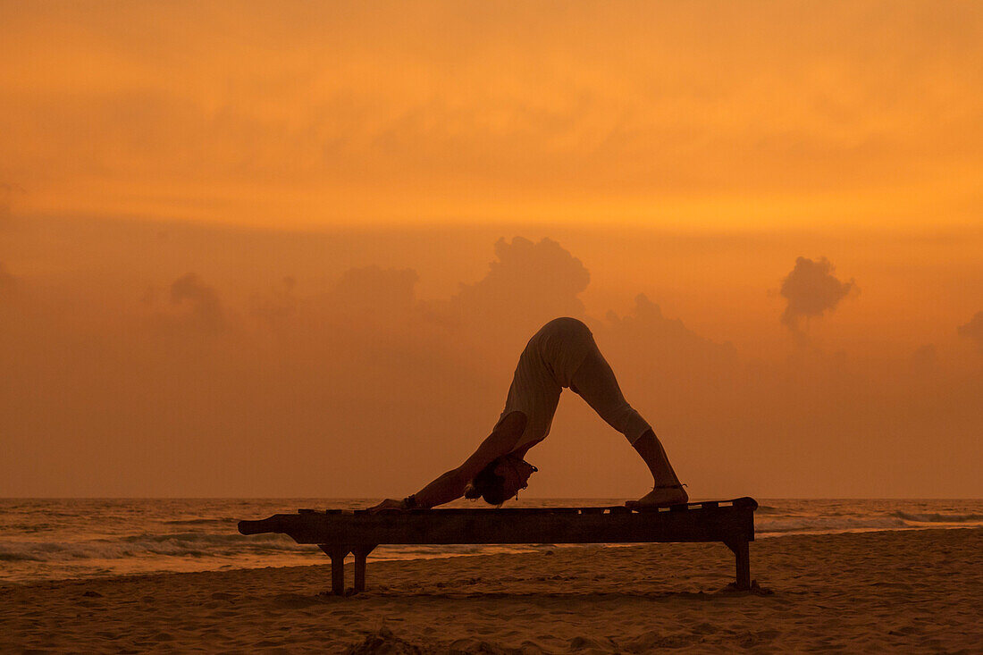 Mädchen macht Yoga bei Sonnenuntergang am Strand von Sri Lanka