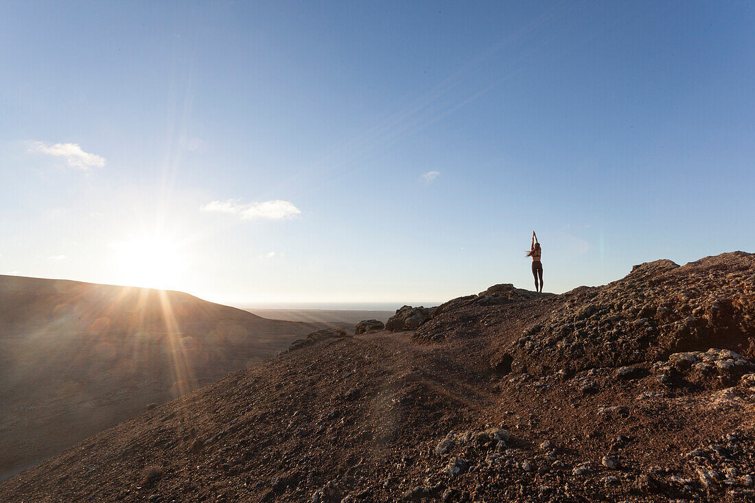 Girl doing yoga on the top of a volcano in Fuerteventura, Canary Islands