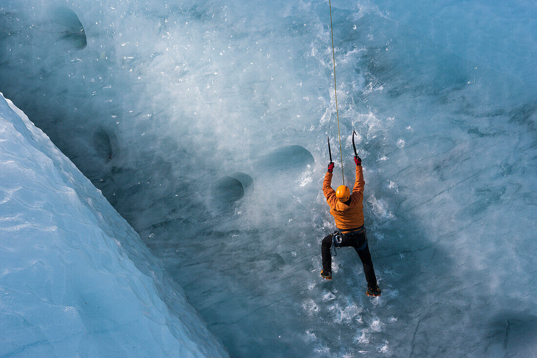 Man climbing a steep glacier ice at the glacier Gigjokull. South Iceland.