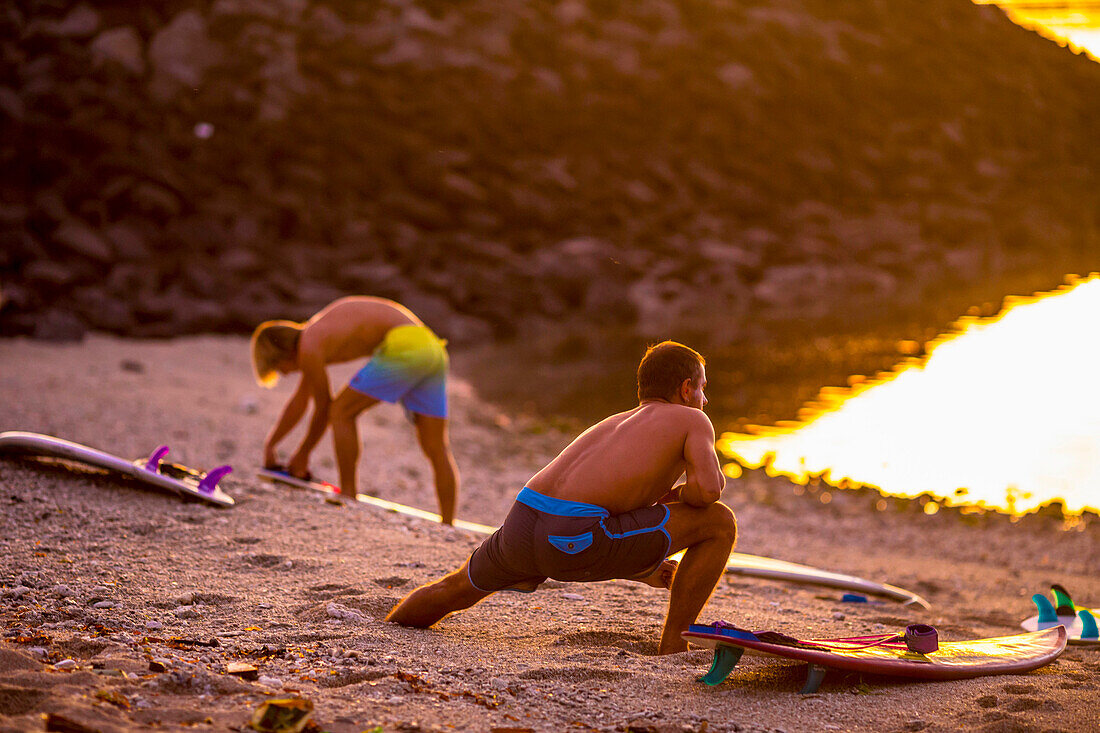 Surfers stretching on the beach before surfing.