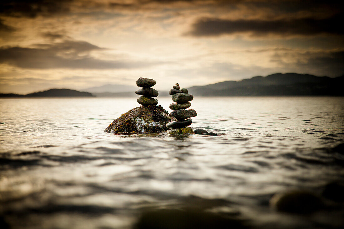 Two small rock stacks are slowly covered by water as the tide rises near Sechelt, BC, Canada.