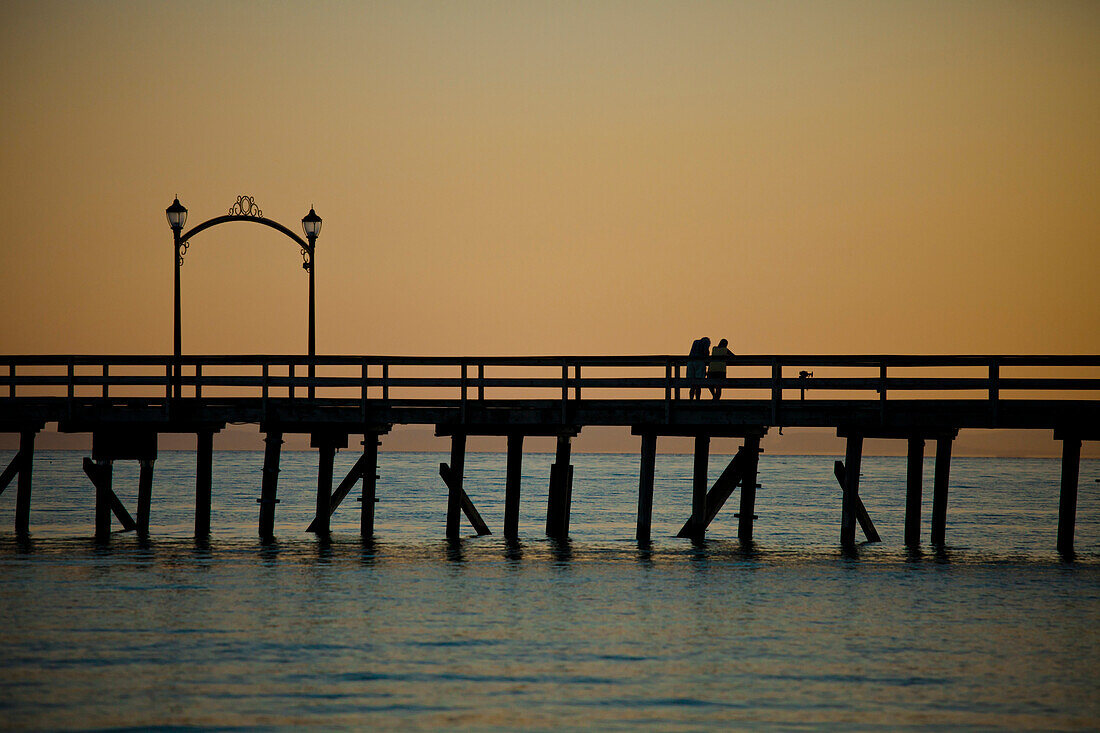 A couple relax on the pier after sunset in White Rock , British Columbia.