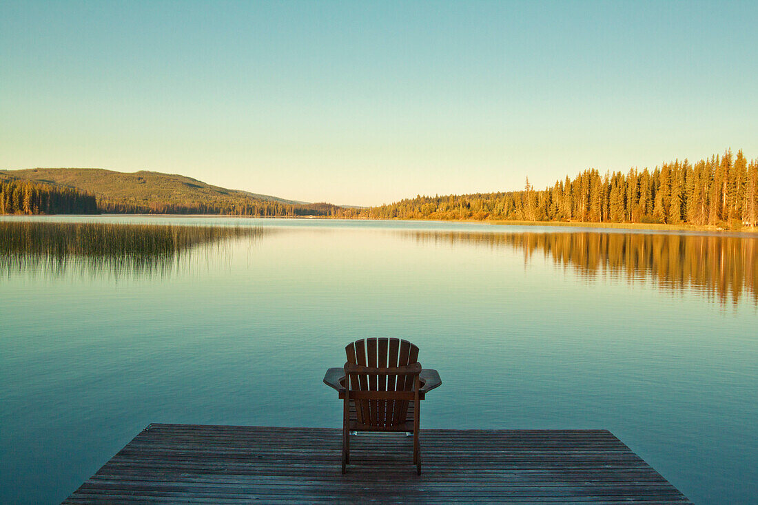 A single chair on a dock looks out toward Lac Le Jeune Lake in British Columbia, Canada.