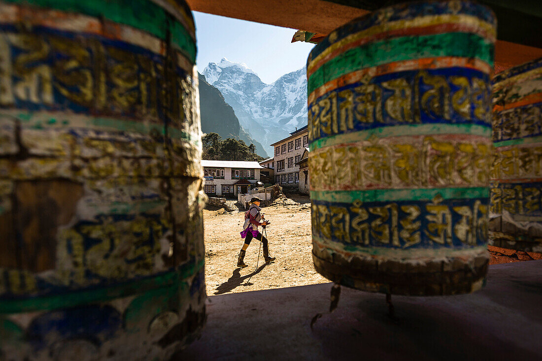 A woman is hiking past prayer wheels at Tengboche Monastery on December 9th 2012, Sagarmatha National Park, Khumbu region, Nepal.